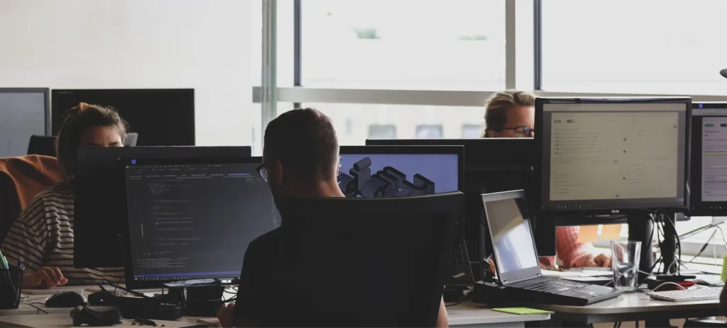 A wide shot of an office environment with several people working at their computers.